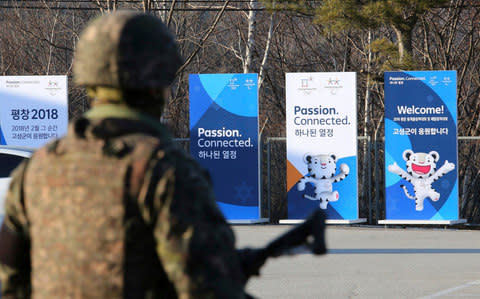 Posters showing the 2018 Pyeongchang Winter Olympic mascot are displayed as a South Korean army soldier stands guard at the Unification Observation post in Goseong, near the border with North Korea - Credit:  AP