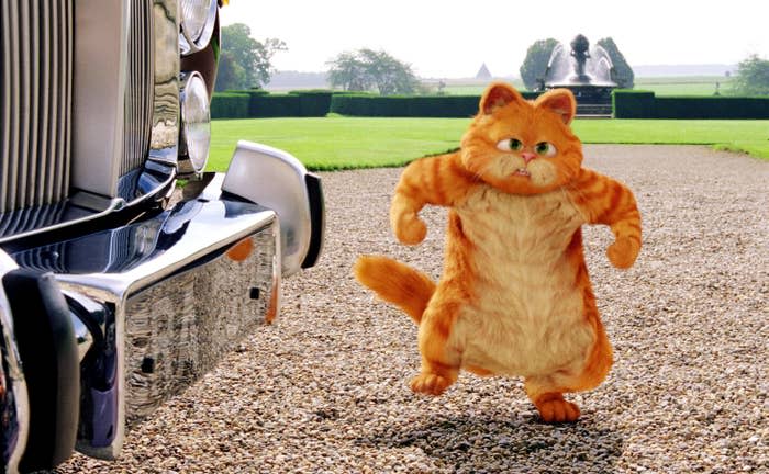 An animated Garfield standing in front of a vehicle with a fountain in the background