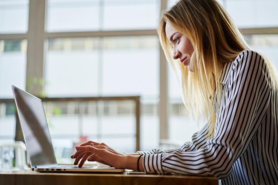 An investor in an office types on a laptop.