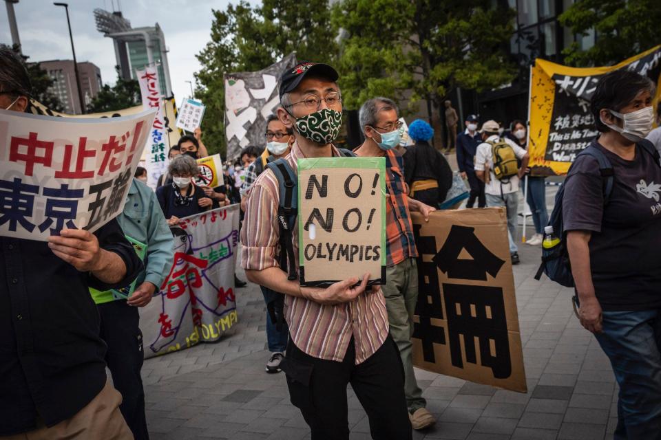 protesters hold signs at a demonstration against the tokyo olympics, may 9 2021