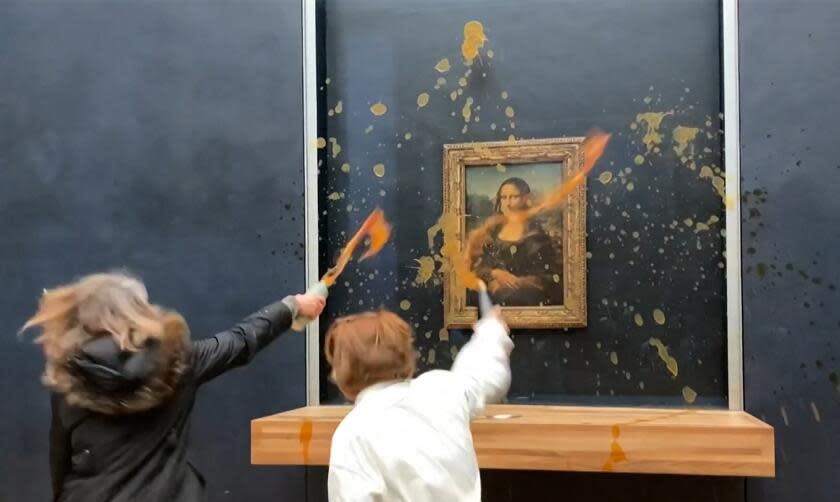 TOPSHOT - This image grab taken from AFPTV footage shows two environmental activists from the collective dubbed "Riposte Alimentaire" (Food Retaliation) hurling soup at Leonardo Da Vinci's "Mona Lisa" (La Joconde) painting, at the Louvre museum in Paris, on January 28, 2024. Two protesters on January 28, 2024 hurled soup at the bullet-proof glass protecting Leonardo da Vinci's "Mona Lisa" in Paris, demanding the right to "healthy and sustainable food", an AFP journalist said. It is the latest attack on the masterpiece in the French capital's Louvre museum, after someone threw a custard pie at it in May 2022, but it's thick glass casing ensured it came to no harm. (Photo by David CANTINIAUX / AFPTV / AFP) (Photo by DAVID CANTINIAUX/AFPTV/AFP via Getty Images)