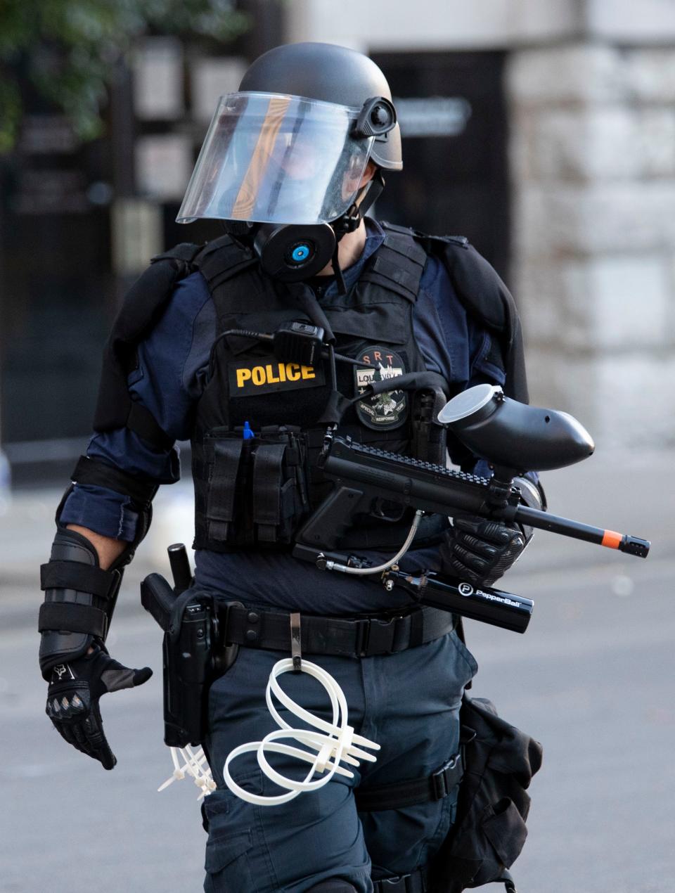 A police officer carries a pepper ball gun May 31 in downtown Louisville.