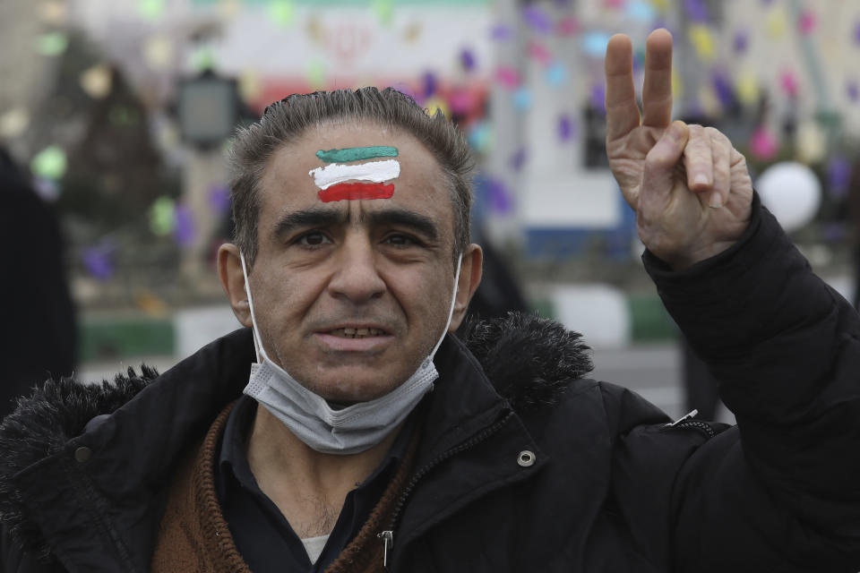 A man flashes a victory sign with the Iranian flag painted on his forehead in the annual rally commemorating the anniversary of Iran's 1979 Islamic Revolution in Azadi (freedom) Square in Tehran, Iran, Friday, Feb. 11, 2022. Thousands of cars and motorbikes paraded in the celebration, although fewer pedestrians were out for a second straight year due to concerns over the coronavirus pandemic. (AP Photo/Vahid Salemi)
