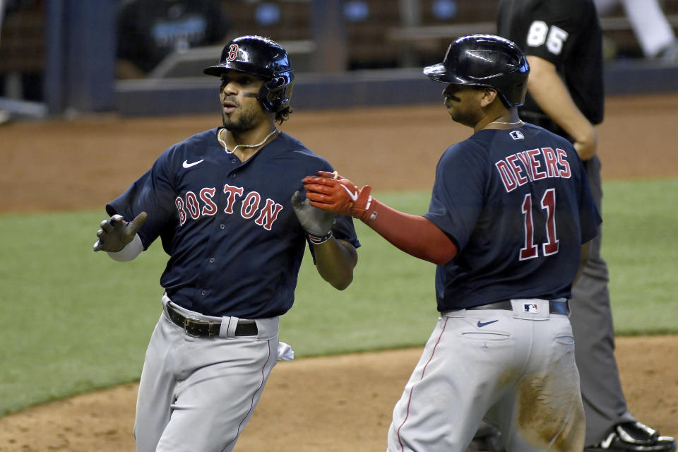 Boston Red Sox's Rafael Devers, right, and Xander Bogaerts celebrate after scoring during the sixth inning of a baseball game against the Miami Marlins, Thursday, Sept. 17, 2020, in Miami. (AP Photo/Gaston De Cardenas)