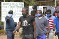 A prison guard directs prisoners following their release from Chikurubi prison on the outskirts of Harare, Saturday, April 17, 2021. Zimbabwe began the release of about 3,000 prisoners under a presidential amnesty aimed at easing congestion and minimizing the threat of COVID-19 across the country's overcrowded jails. (AP Photo/Tsvangirayi Mukwazhi)