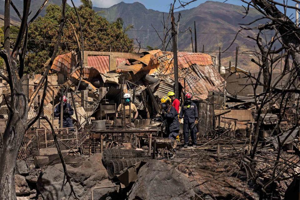 <p>YUKI IWAMURA/AFP via Getty</p> Search and recovery team members check charred buildings and cars in the aftermath of the Maui wildfires in Lahaina, Hawaii, on August 18, 2023.