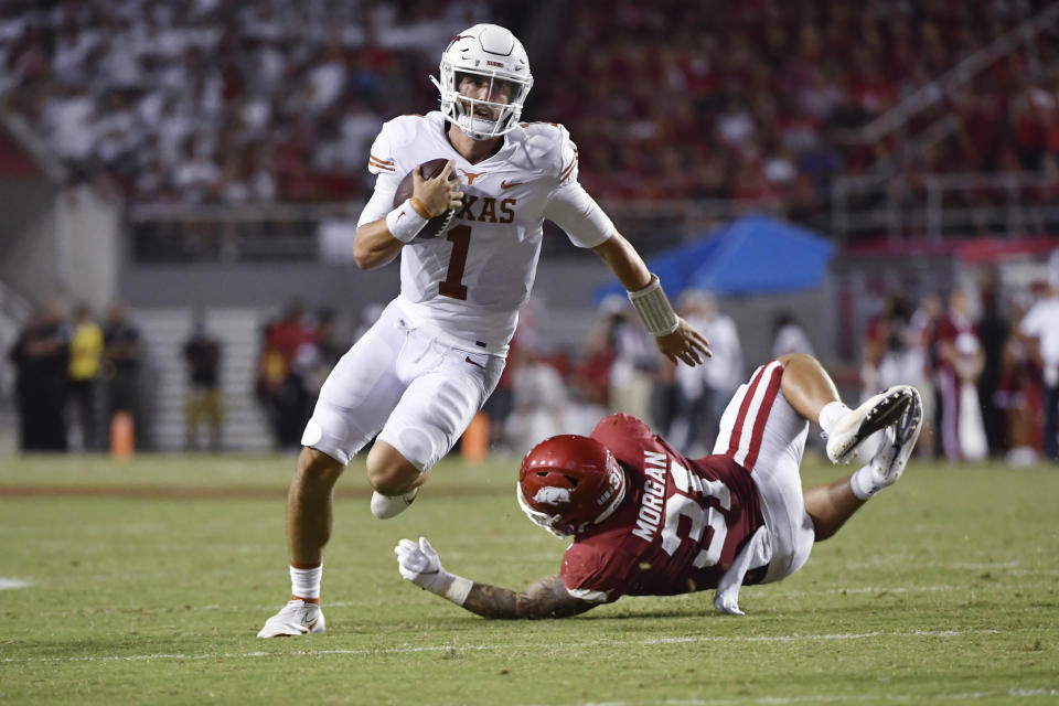 Texas quarterback Hudson Card (1) slips past Arkansas defensive back Grant Morgan (31) as he runs the ball during the second half of an NCAA college football game Saturday, Sept. 11, 2021, in Fayetteville, Ark. (AP Photo/Michael Woods)