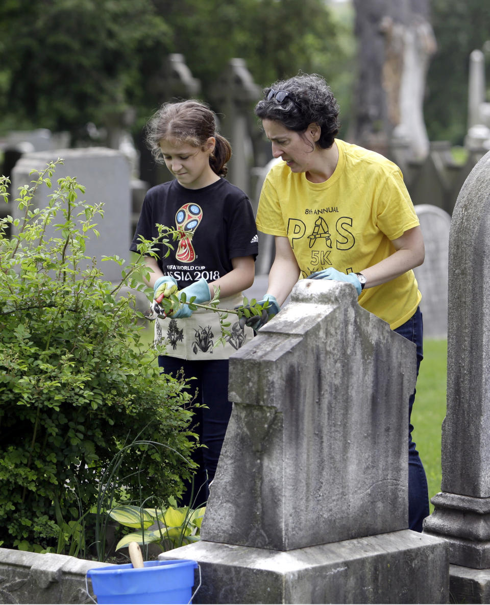 Celina Gray, right, and her daughter Kalliope Kourelis, trim a rose bush growing on the cradle grave of Mary Glenn, at the Woodlands Cemetery, Saturday May 4, 2019 in Philadelphia. The cemeteries of yore existed as much the living as for the dead. And a handful of these 19th century graveyards are restoring the bygone tradition of cemetery gardening. (AP Photo/Jacqueline Larma)