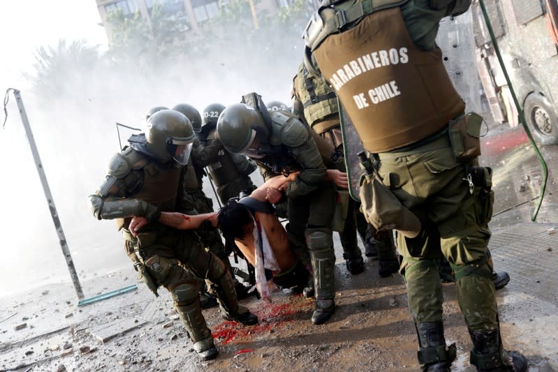 ATENCIÓN EDITORES, ESTE MATERIAL CONTIENE UNA IMAGEN SENSIBLE. Un manifestante herido es llevado por agentes de seguridad en una protesta en Santiago, Chile