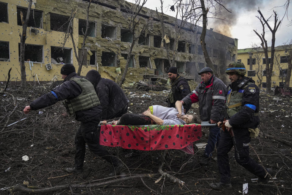 FILE - Ukrainian emergency employees and police officers evacuate injured pregnant woman Iryna Kalinina, 32, from a maternity hospital that was damaged by a Russian airstrike in Mariupol, Ukraine, March 9, 2022. On the battlefields of Ukraine, the fog of war plagues soldiers. A related issue afflicts those who are far from the fighting but avid to learn developments in the vast war. Disinformation, misinformation and absent information all cloud civilians’ understanding. Officials from each side denounce devious plots being prepared by the enemy, which never materialize. They claim victories that can’t be confirmed and stay quiet about defeats. (AP Photo/Evgeniy Maloletka, File)