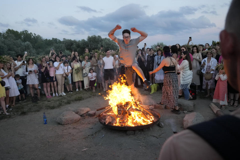 A Ukrainian man jumps over fire during a traditional Ukrainian celebration of Kupalo Night, in Warsaw, Poland, on Saturday, June 22, 2024. Ukrainians in Warsaw jumped over a bonfire and floated braids to honor the vital powers of water and fire on the Vistula River bank Saturday night, as they celebrated their solstice tradition of Ivan Kupalo Night away from war-torn home. (AP Photo/Czarek Sokolowski)