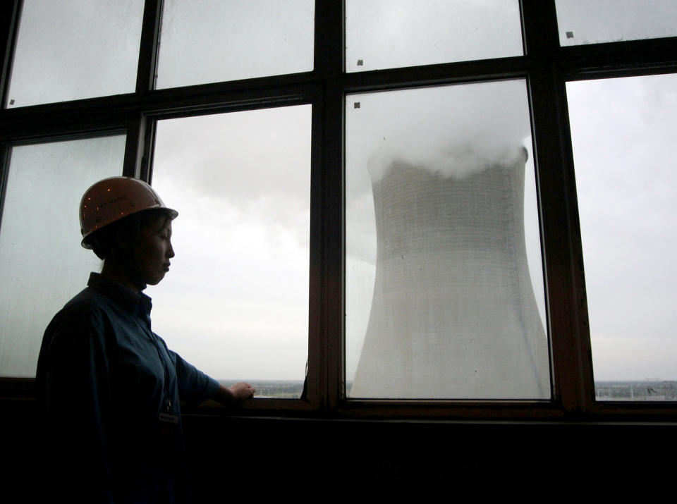 A worker looks out a window at a cooling tower at the Datang (Natalie Behring / Bloomberg via Getty Images file)