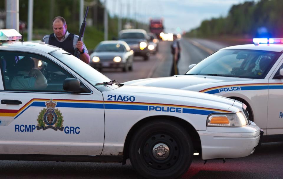 RCMP officers use their vehicle to create a keep a perimeter in Moncton, N.B.on Wednesday June 4, 2014. The RCMP in New Brunswick says an undisclosed number of people have been shot and a manhunt is underway in the north end of Moncton for a man armed with guns. 