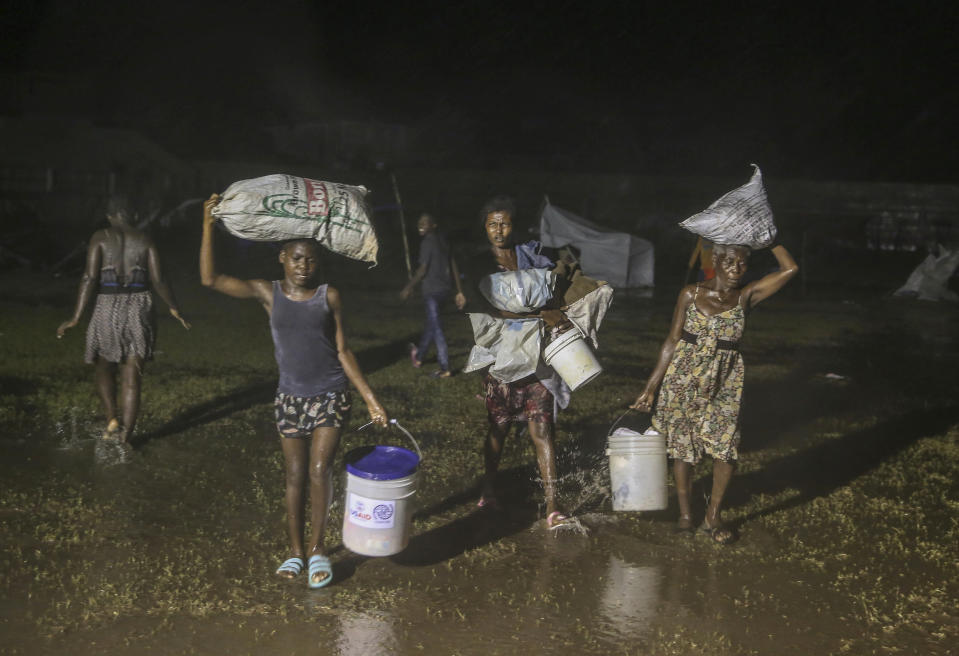 People affected by Saturday's earthquake walk under the rain of Tropical Depression Grace at a refugee camp in Les Cayes, Haiti, Monday, Aug. 16, 2021. (AP Photo/Joseph Odelyn)