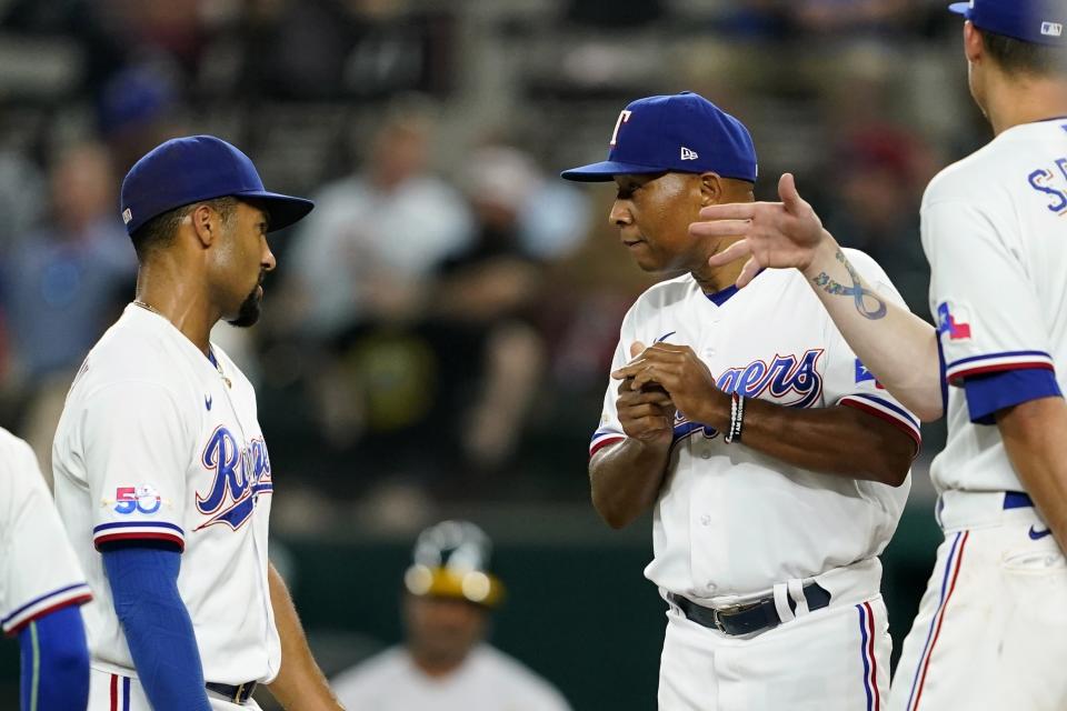 Texas Rangers' Marcus Semien, left, and Corey Seager, right, talk with interim manager Tony Beasley, center, on the mound after Beasley pulled starting pitcher Kohei Arihara in the sixth inning of a baseball game in Arlington, Texas, Tuesday, Aug. 16, 2022. (AP Photo/Tony Gutierrez)