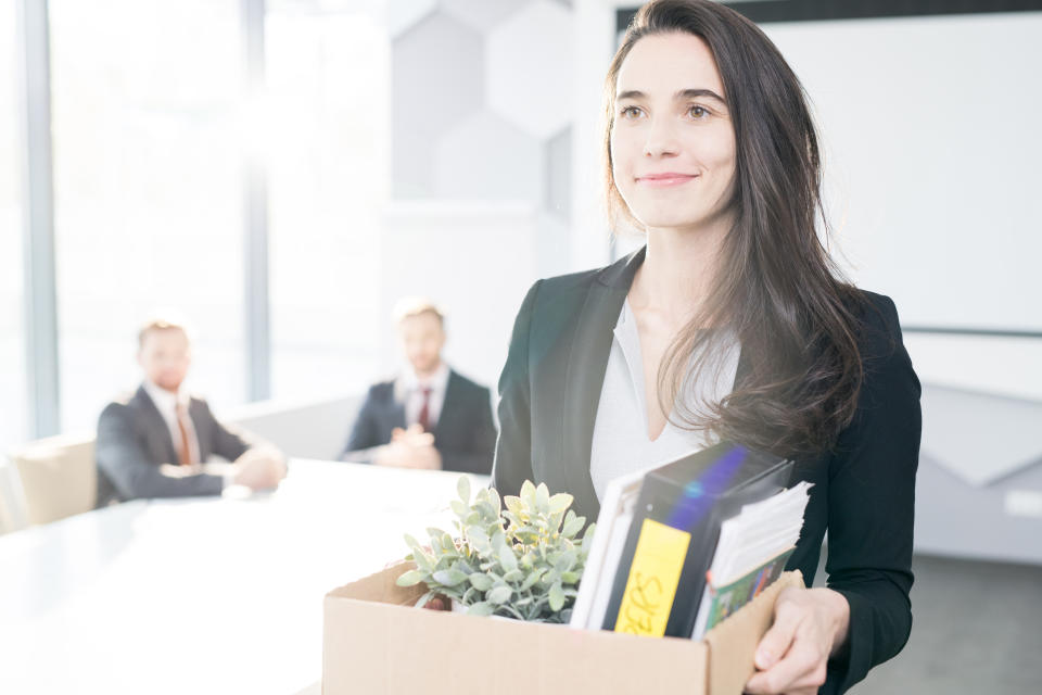 A woman leaving an office carrying her possessions after resigning