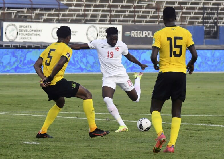 Canada's Alphonso Davies fights for the ball against Jamaica's Alvas Powell and Je-vaughn Watson