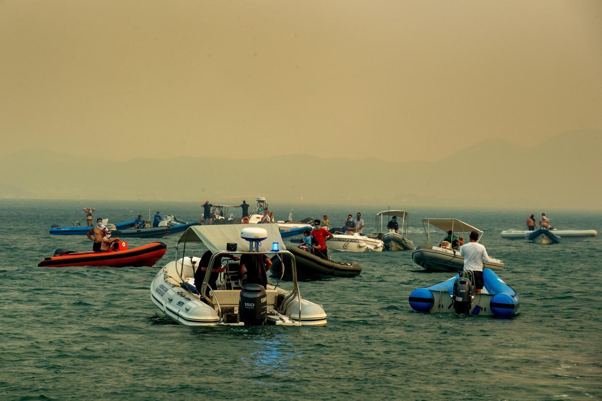 People evacuate by boats during a wildfire at Nea Anchialos, near Volos, Greece (EPA)