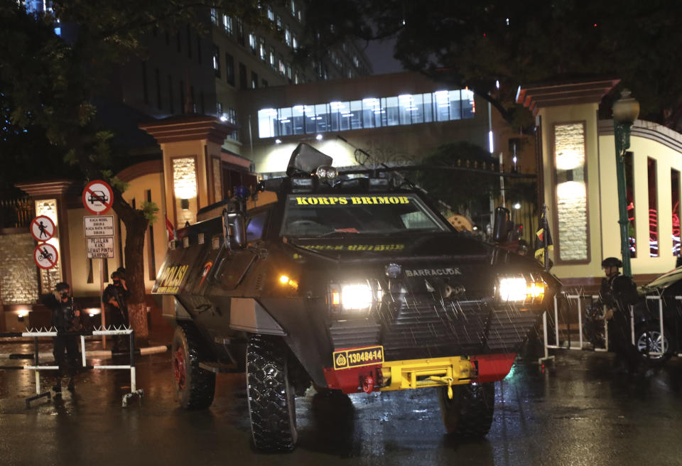 Police officers stand guard near an armored vehicle at the National Police Headquarters following a suspected militant attack in Jakarta, Indonesia, Wednesday, March 31, 2021. A woman entered the Indonesian National Police Headquarters in Jakarta and pointed a gun at several officers before being shot dead by police, in the latest in a series of militant attacks in the world's most populous Muslim nation. (AP Photo/Dita Alangkara)