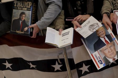 Supporters of U.S. Republican presidential candidate Donald Trump hold items they are hoping to get signed at a campaign event in Pella, Iowa, United States, January 23, 2016. REUTERS/Jim Young