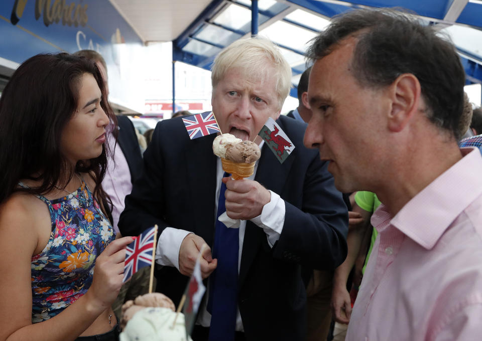 FILE - In this Saturday, July 6, 2019 file photo Conservative Party leadership candidate Boris Johnson, centre, eats an ice cream in Barry Island, Wales. (AP Photo/Frank Augstein, File)