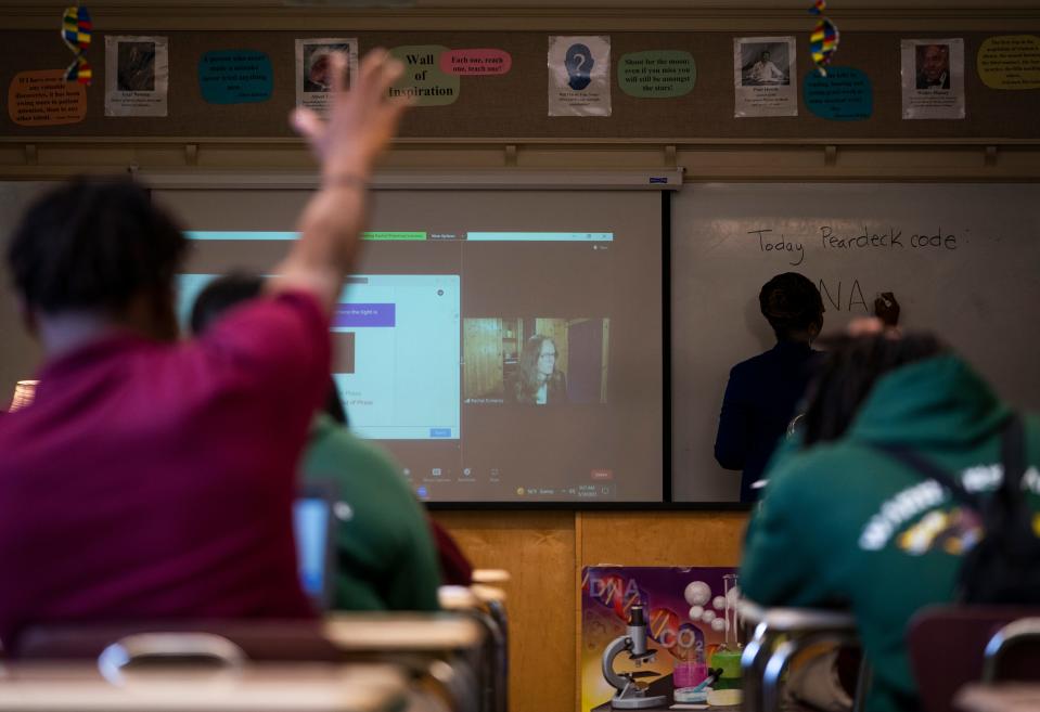 Thurgood Marshall Academy Public Charter High School Science students watch their instructor Rachel Pomeroy, on screen, during class in May as the instructor taught the class virtually broadcast virtually through the Owl Labs Meeting Owl 3 camera.