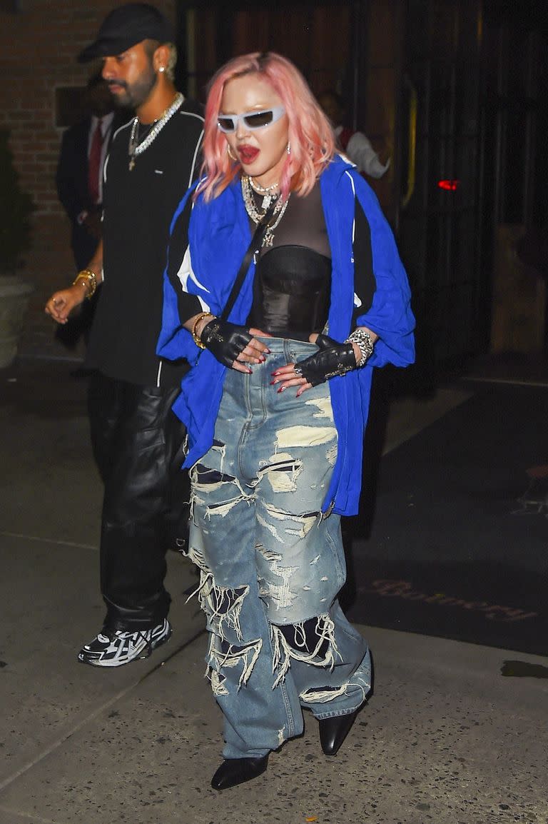 Una elegante Madonna es escoltada por su seguridad fuera del Bowery Hotel en la Ciudad de Nueva York después de asistir a una fiesta posterior; la legendaria artista luce su cabello teñido de rosa claro