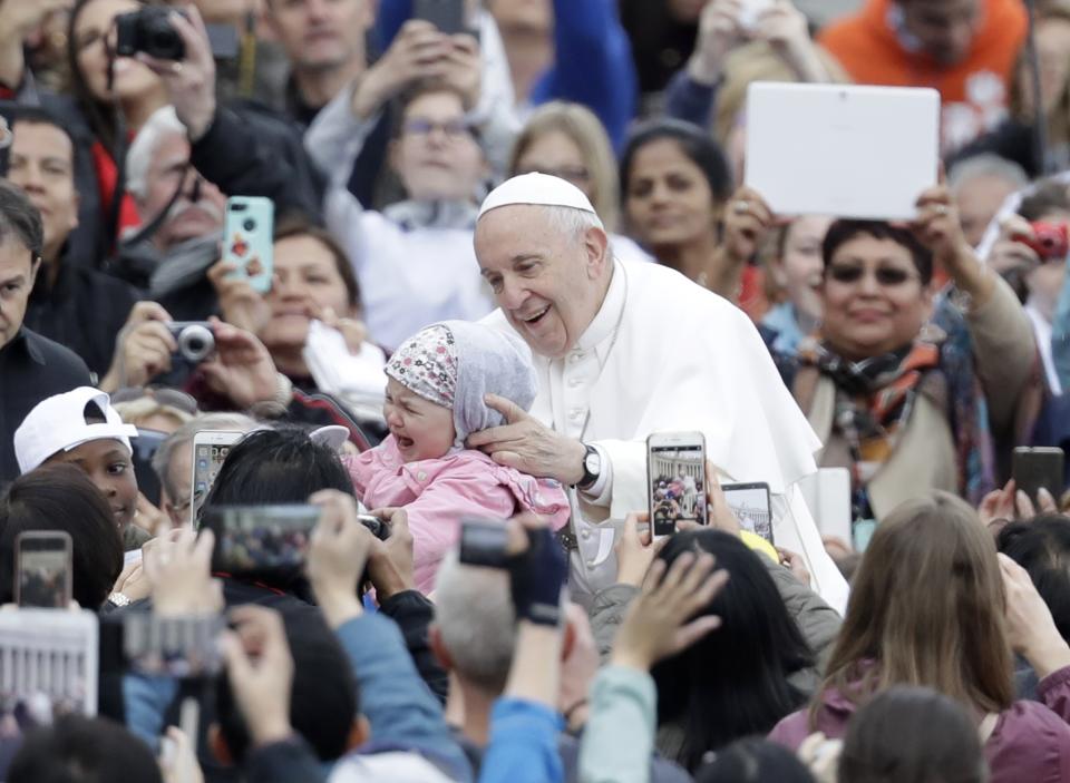 Pope Francis is given a child to bless as he is driven through the crowd during his weekly general audience in St. Peter's Square, at the Vatican, Wednesday May 15, 2019. (AP Photo/Andrew Medichini)