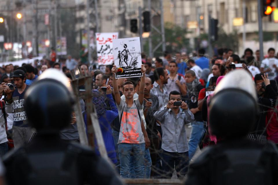 Demonstrators protest in front of the presidential palace in Cairo, Egypt, Saturday, April 26, 2014. Hundreds of secular-minded activists and protesters rallied in front of the presidential palace Saturday, demanding the interim president abolish a disputed protest law used extensively over the past months to jail and prosecute activists, including leading figures of the 2011 uprising that toppled longtime autocrat Hosni Mubarak. Arabic in poster in center reads: "Drop law and get them out of prison".