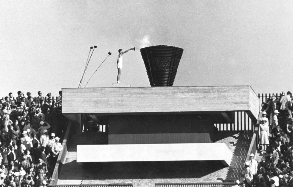 FILE - In this Oct. 10, 1964 file photo, Japanese runner Yoshinori Sakai lights the Olympic cauldron during the opening ceremony of the 1964 Summer Olympics in Tokyo. Sakai was born in Hiroshima on Aug. 6, 1945, the day the nuclear weapon destroyed that city. He symbolized the rebirth of Japan after the Second World War as he opened the 1964 Tokyo Games. Sakai was born in Hiroshima on Aug. 6, 1945, the day the United States dropped an atomic bomb on the city. Just over 19 years later, he ran with the Olympic flame into the national stadium, left the cinder track, and jogged up a long flight of flower-lined stairs to reach the top. (AP Photo/File)