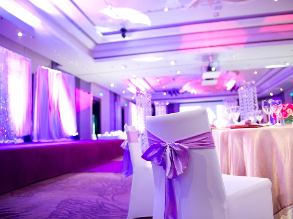 Chairs and table next to dance floor at wedding. Scene is illuminated in purple light