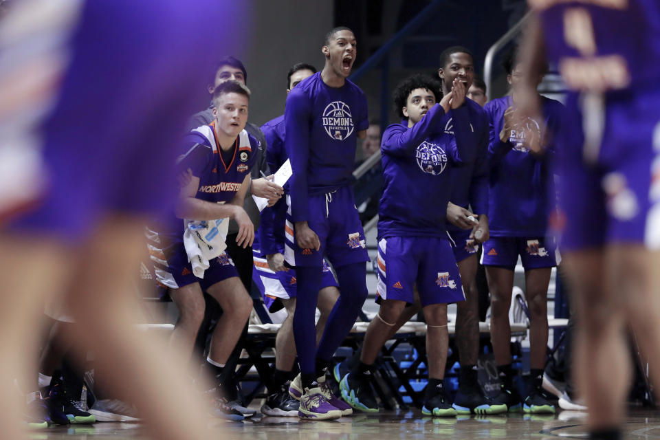 Hansel Enmanuel, center, a freshman guard from the Dominican Republic for Northwestern State, cheers a score with his teammates from the bench during an NCAA college basketball game against Rice Saturday, Dec. 17, 2022, in Houston. Enmanuel lost his left arm in a childhood accident and has attained the talent and skill to play at the college level. (AP Photo/Michael Wyke)