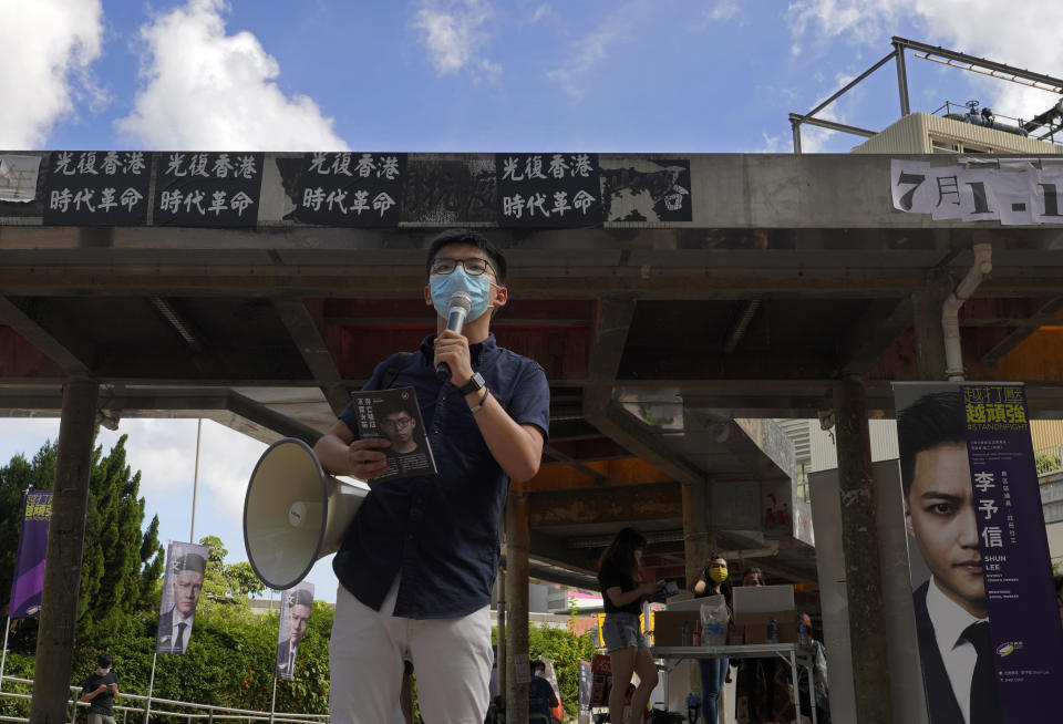 Activist Joshua Wong uses a megaphone to urge passers-by outside a subway station to take part in voting in Hong Kong Saturday, July 11, 2020, in an unofficial "primary" for pro-democracy candidates ahead of legislative elections in September. At least 12 Hong Kong pro-democracy nominees including Joshua Wong were disqualified for a September legislative election, with authorities saying Wednesday, July 29, they failed to uphold the city's mini-constitution and pledge allegiance to Hong Kong and Beijing. (AP Photo/Vincent Yu)