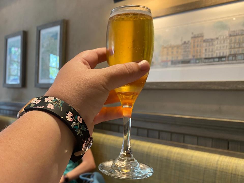 Hand holding up flute of French cider at Le Creperie de Paris at EPCOT