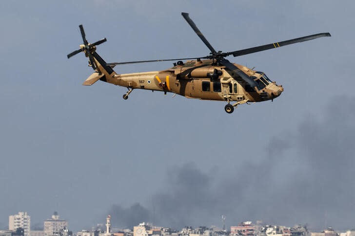 Un helicóptero militar israelí vuela mientras el humo se eleva sobre Gaza, en medio del conflicto en curso entre Israel y el grupo islamista palestino Hamás, visto desde el sur de Israel,