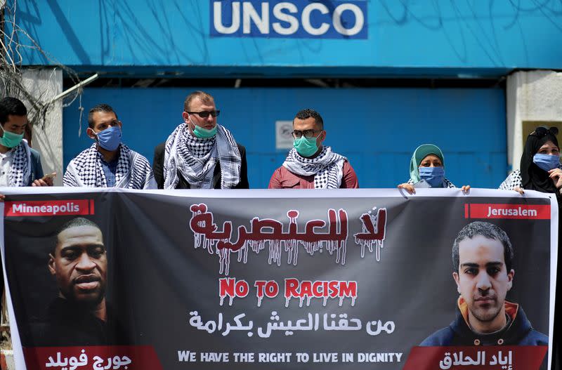 Palestinians hold a banner with pictures of George Floyd and and Iyad al-Halaq, during a protest against racial inequality, in Gaza City