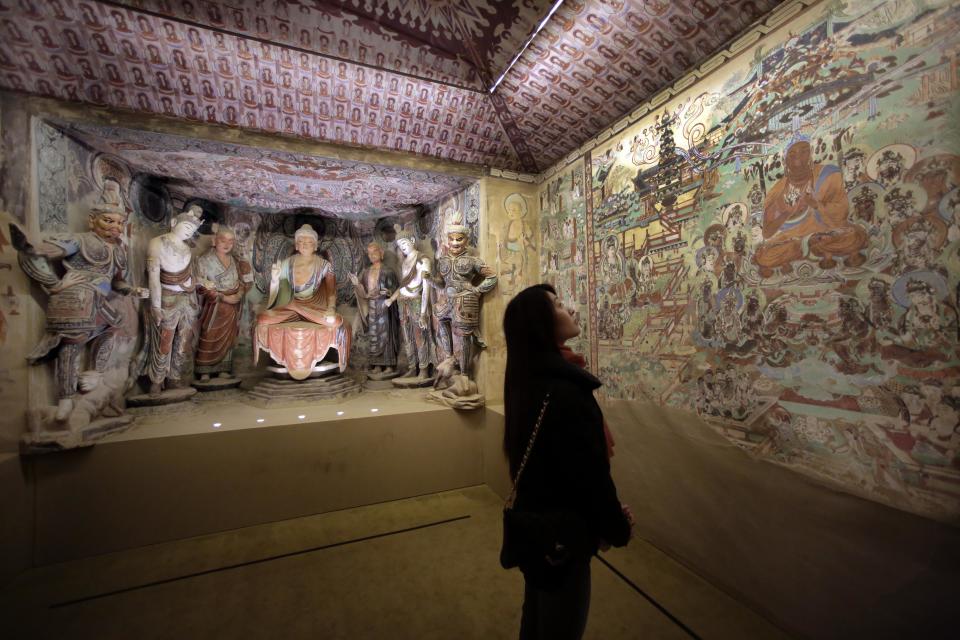 A woman views a full scale replica cave from the 8th century that contains the Bodhisattva of the Mogao Caves, in "Dunhuang: Buddhist Art at the Gateway of the Silk Road," at the China Institute, in New York, Tuesday, April 24, 2013. (AP Photo/Richard Drew)