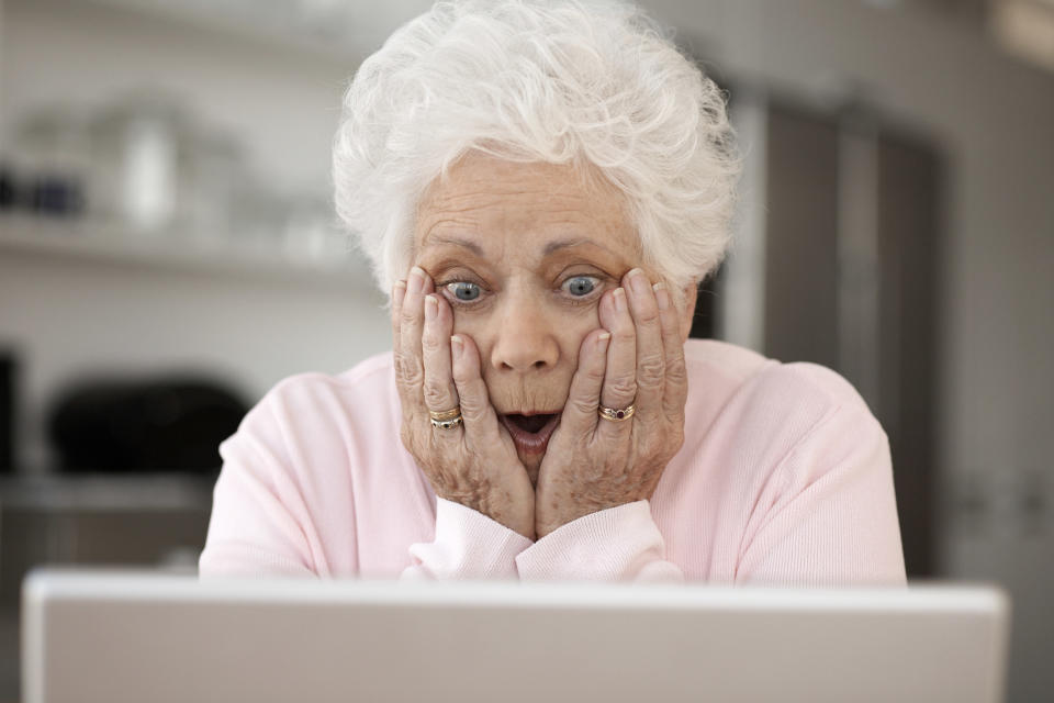 A woman appearing astonished and staring at a computer