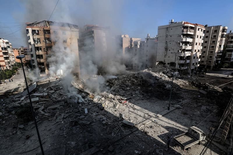 Smoke billows from destruction of buildings targeted by Israeli air raids at a street in Beirut southern suburb. Stringer/dpa