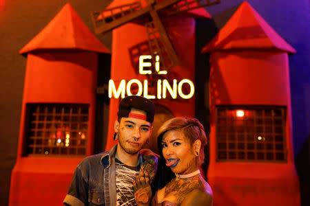 Tattoo artists, Kathriel Zambrano (L), 23, and Yohanna Gonzalez, 28, pose for a portrait in front of the bar El Molino where they first met, in Caracas, Venezuela, February 9, 2018. Yohanna was working at a bar for an event called InkFest. She was piercing. Meanwhile, Kathriel was being tattooed in front of a stand where she was working. "I didn't give him much attention, because, at the time, I was with another person," said Yohanna. He didn't stop looking at her and tried some pick up lines. "When I saw him, he impressed me because he has very big eyes and the colour was very impressive but nothing else. I left early." One day he texted and asked her what she was doing and if he could go and visit. "He bought me a bottle of anise liquor, but I told him, 'honey, I don't drink, you can buy me a chocolate if you want.' One day she arrived home and "on my bed there was a gift bag in the shape of candy, with a lot of makeup, a necklace and a little book that said, 'do you want to be my girlfriend?' and that's where it started..." They have been together for over five months now. "One day he grabbed me in a queue, and asked me if I really wanted something serious with him, I said yes, I was willing to be with him forever. Then he knelt, gave me a ring and proposed to me. I started laughing a lot because I got very nervous." Now they are engaged. "We have not been together for long time, but we really feel that we know each other all our lives, it was such a brutal chemistry at the beginning that it has been impressive," said Yohanna. REUTERS/Carlos Garcia Rawlins