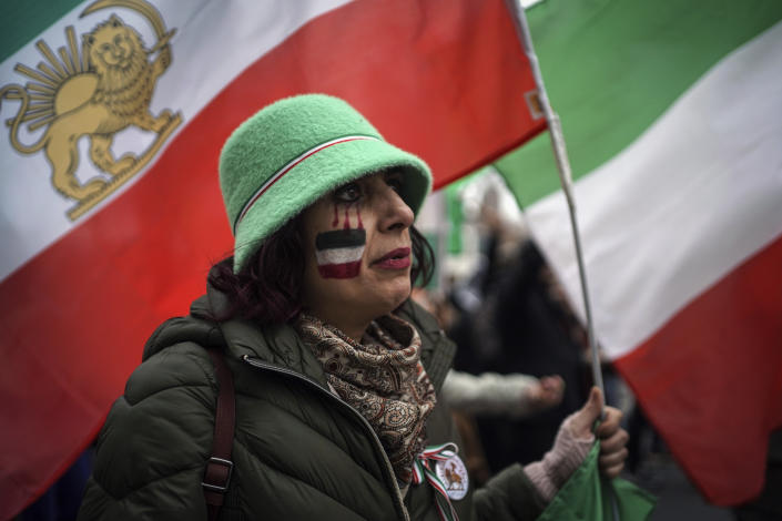 A woman holds a flag as people demonstrate in Lyon, central France, Sunday, Jan. 8, 2023. Hundreds of people marched Sunday in France to honor an Iranian Kurdish man who took his own life in a desperate act of anguish over the nationwide protests in Iran. Police estimated the size of the crowd that gathered for Mohammad Moradi at about 1,000 people. They marched in the city of Lyon, where the 38-year-old Moradi took his own life in December, drowning in the Rhone river. (AP Photo/Laurent Cipriani)