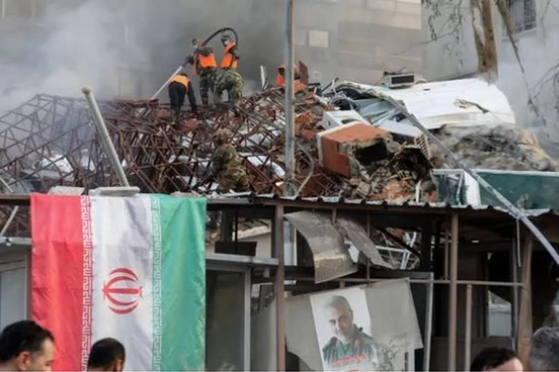 Emergency and security personnel extinguish a fire at the site of strikes which hit a building annexed to the Iranian embassy in Syria's capital Damascus