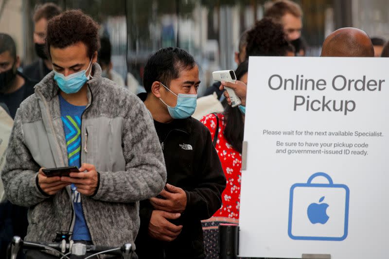 FILE PHOTO: A customer has his temperature taken while in line outside an Apple Store to pick up Apple's new 5G iPhone 12 in Brooklyn, New York