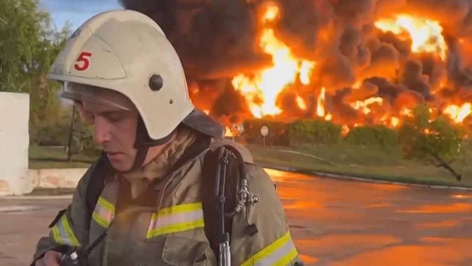 This video grab taken from a footage released on April 29, 2023, on the Telegram chanel of Mikhail Razvozhayev, the Moscow-installed governor of Sevastopol, shows a firemen standing next to a huge fire at a fuel depot in Sevastopol (TELEGRAM/ @razvozhaev/AFP via G)