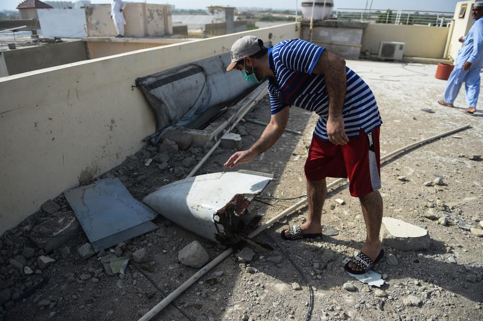 A man checks a part of a Pakistan International Airlines aircraft after it crashed in a residential area in Karachi on May 22, 2020. - A Pakistani plane with nearly 100 people on board crashed into a residential area in the southern city of Karachi on May 22, killing several people on the ground. (Photo by Rizwan TABASSUM / AFP) (Photo by RIZWAN TABASSUM/AFP via Getty Images)