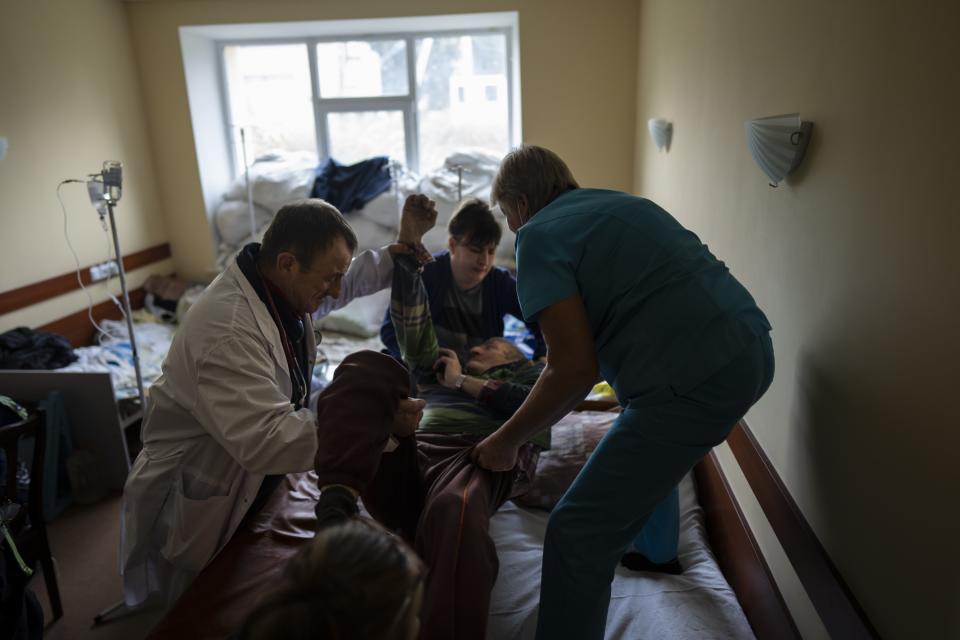 Dr. Yurii Kuznetsov, left, helps nurses to move an elderly patient onto a bed at the hospital in Izium, Ukraine, Sept. 17, 2022. The image was part of a series of images by Associated Press photographers that was a finalist for the 2023 Pulitzer Prize for Feature Photography. (AP Photo/Evgeniy Maloletka)