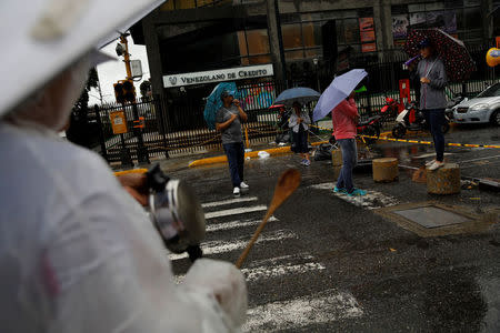 A demonstrator bangs a pot next to a blocked street at a rally against Venezuelan President Nicolas Maduro's government in Caracas, Venezuela, July 19, 2017. REUTERS/Carlos Garcia Rawlins