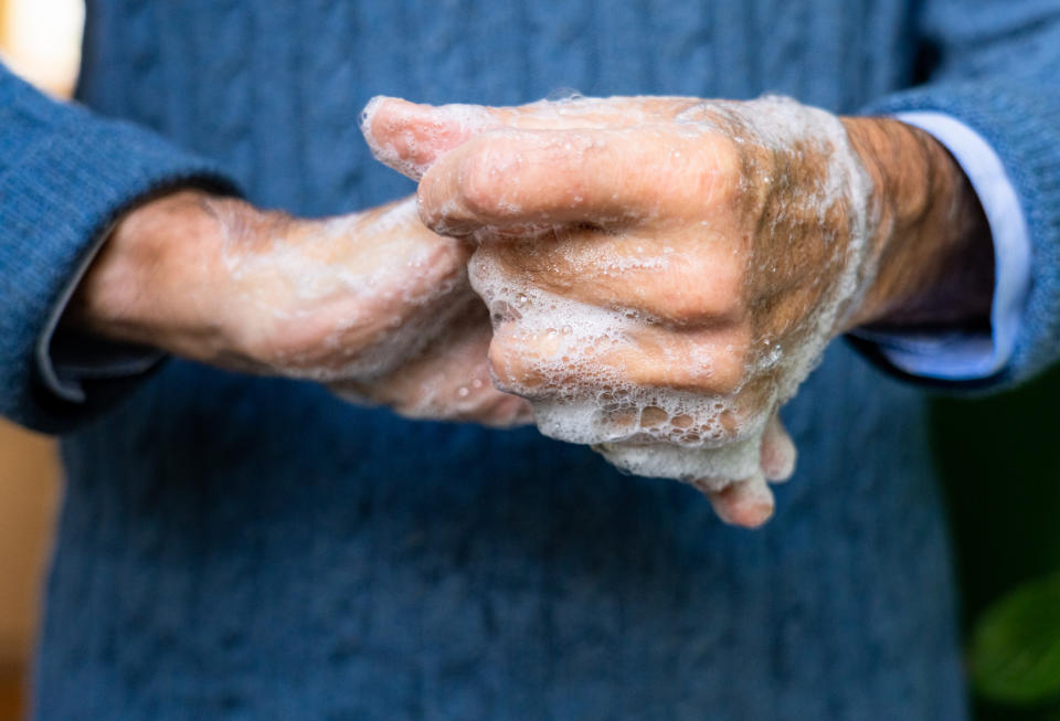 Close-up of an elderly man's hands as he carefully washes them with soap.