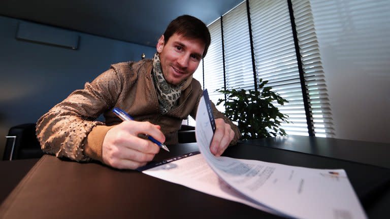 A handout picture taken and released on February 7, 2013 by Barcelona shows Lionel Messi signing his new contract with the club. Messi has extended his contract until 2018