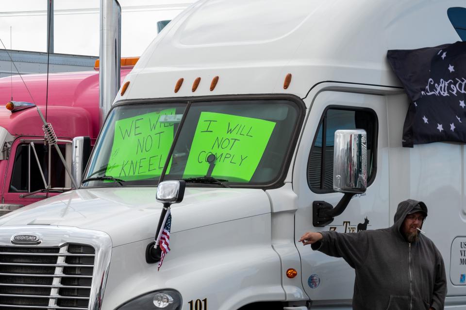 A trucker stands in front of his rig at the People's Convoy rally, a movement opposing COVID-19 mandates, in Adelanto Stadium in Adelanto on Wednesday, Feb. 23, 2022.